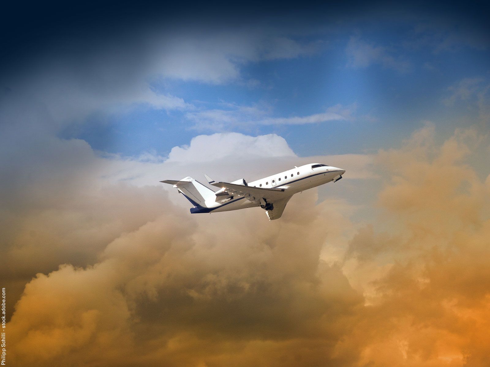A jet aircraft flying in front of orange-colored clouds.