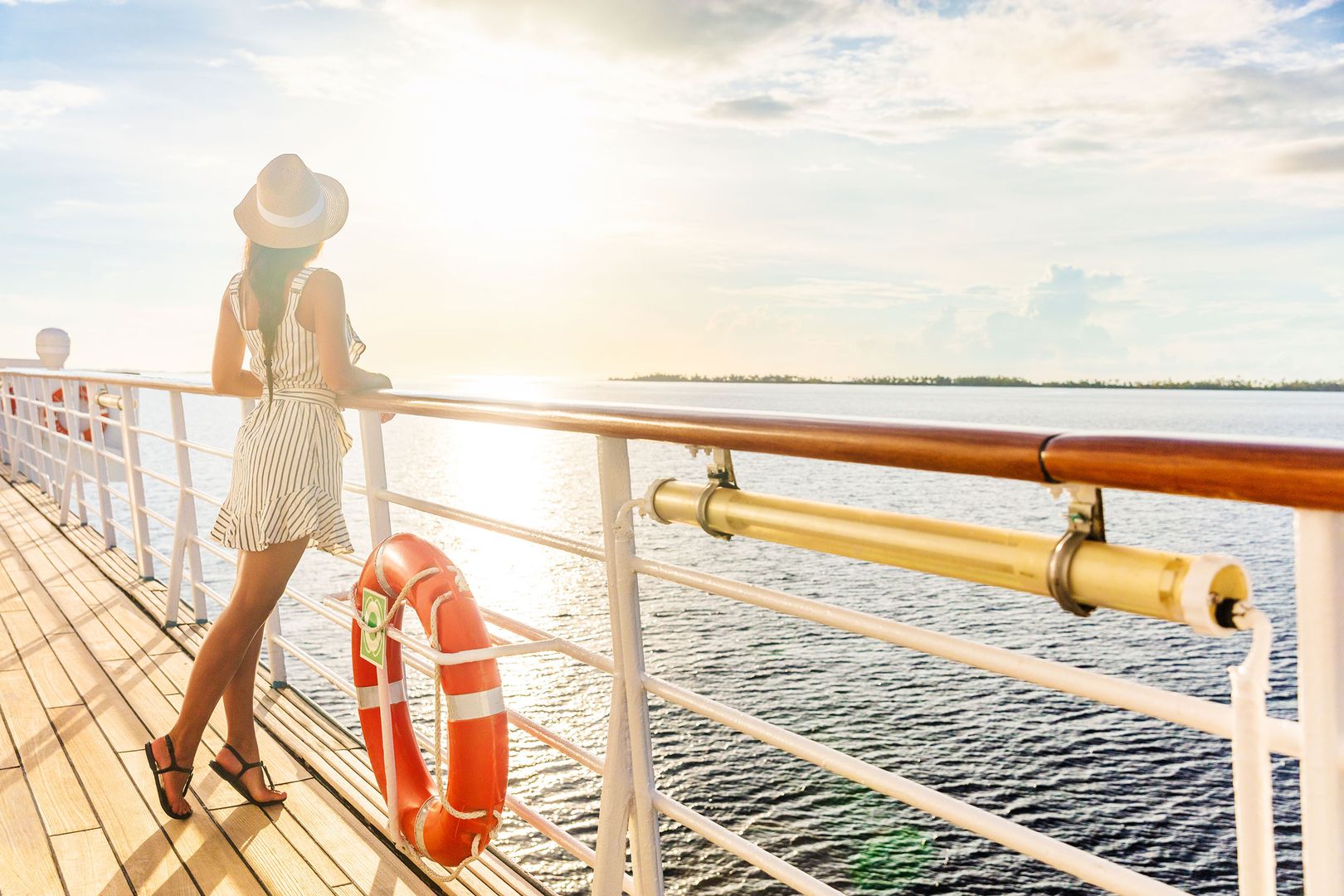 Frau steht an Deck eines Kreuzfahrtschiffs