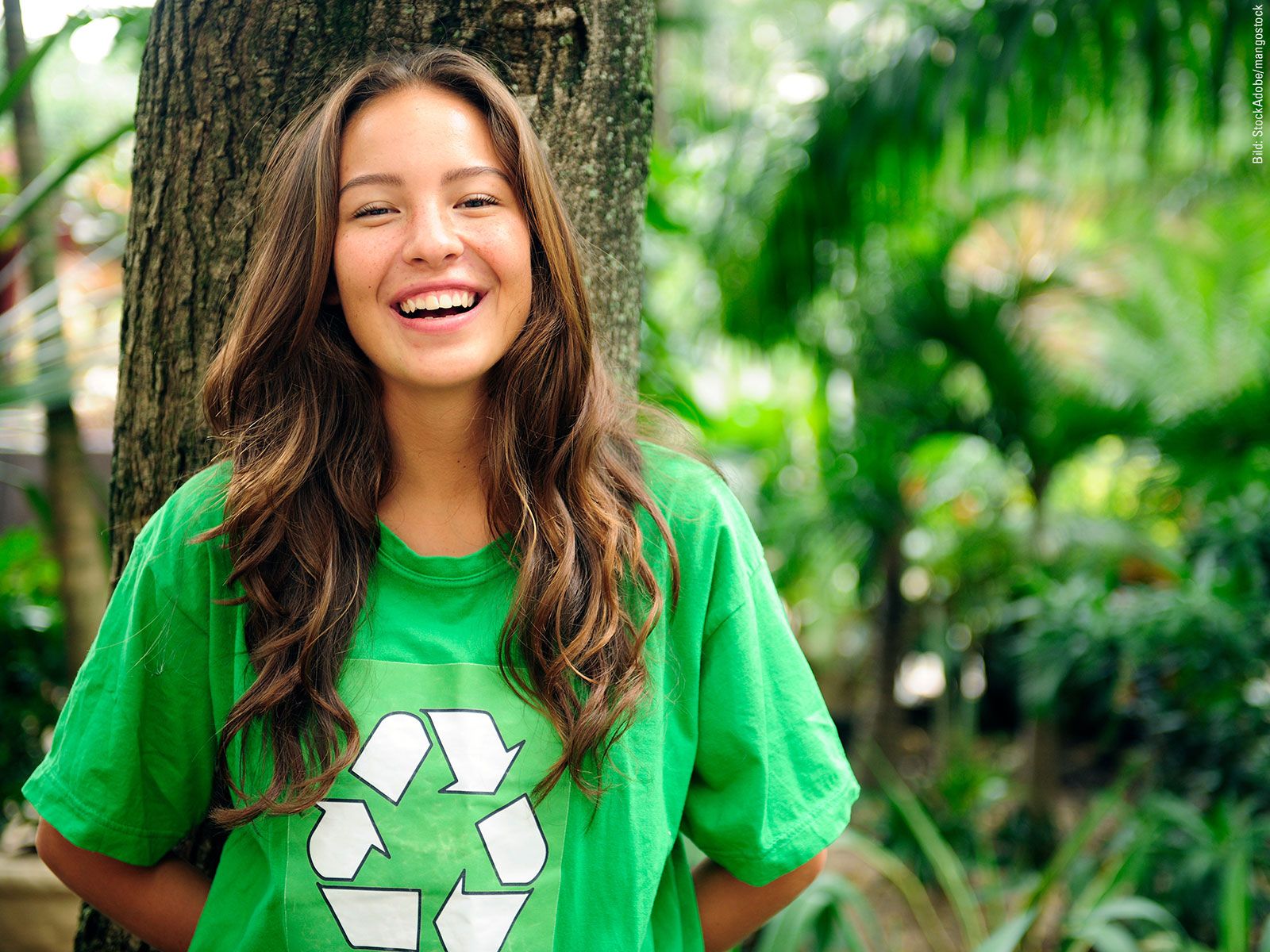 A young woman wearing a green T-shirt with a recycling symbol printed on it.