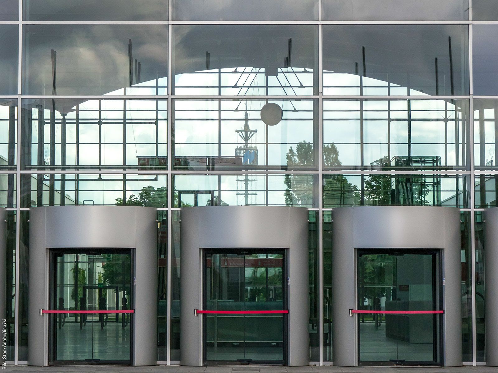 Three elevators in front of a glass building.