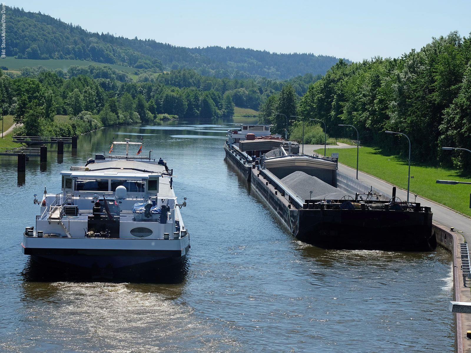 Two boats on a canal flowing through a green landscape.