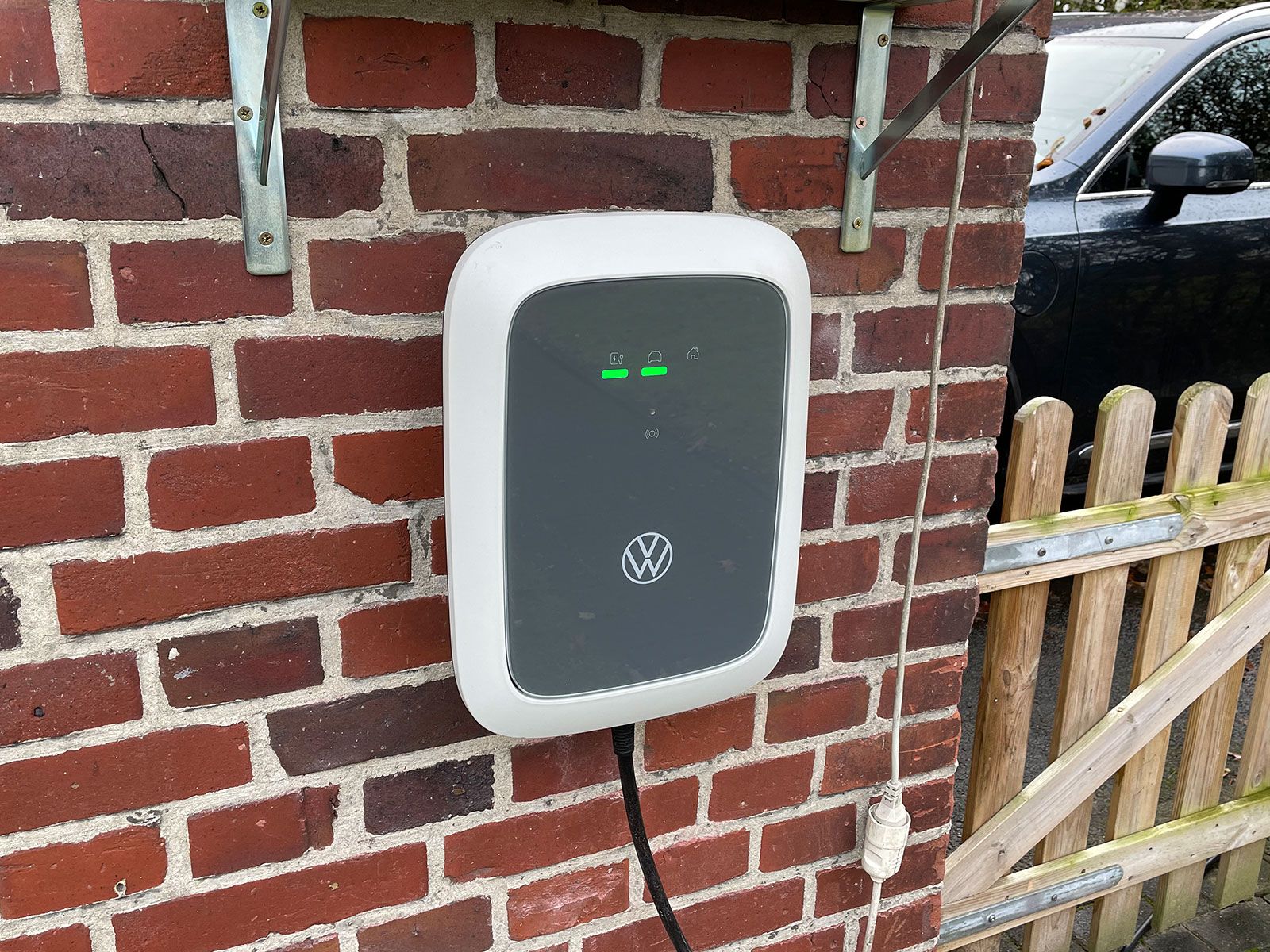 A VW wallbox mounted on a brick wall.