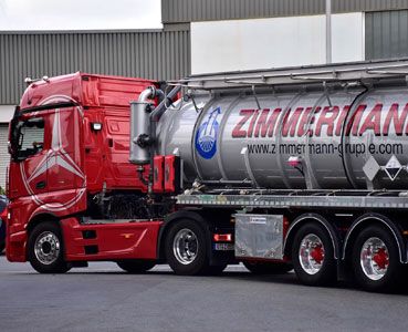 Ein roter LKW mit grauem Anhänger von Zimmermann